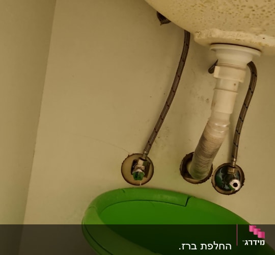 צנרת מתחת לכיור עם דלי ירוק